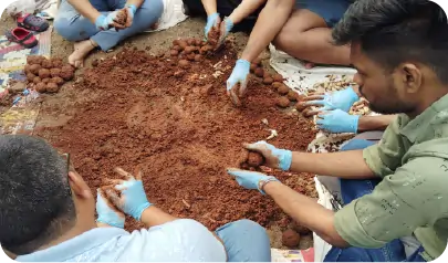 Volunteers mixing soil and seeds while preparing seedballs during CSR activity 